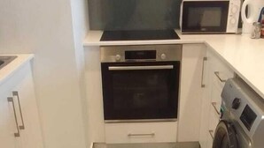 Cocina compacta con horno integrado, microondas y lavadora.