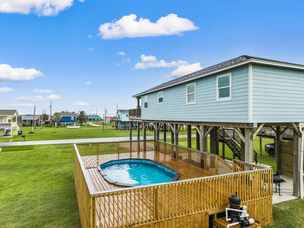 Una propiedad residencial con terraza de madera, piscina y zona de patio cubierta.