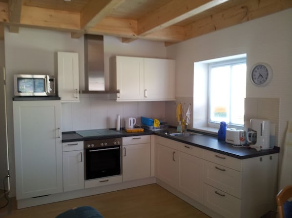 A compact kitchen with white cabinets, a microwave, an oven, and a sink.
