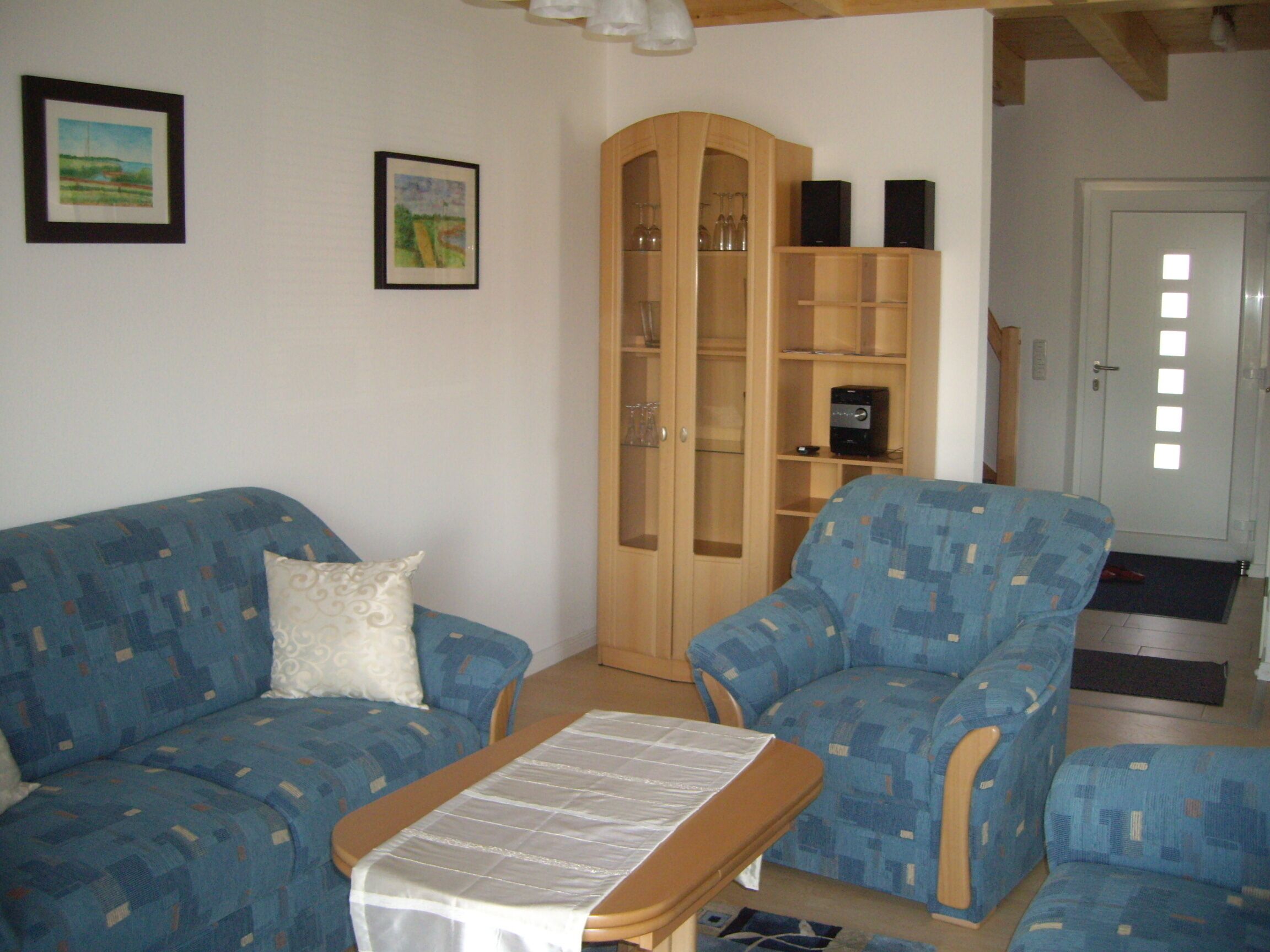 Ein Wohnzimmer mit einem blauen, gemusterten Sofa, einem passenden Sessel und einer Holzkabine mit Glastüren.