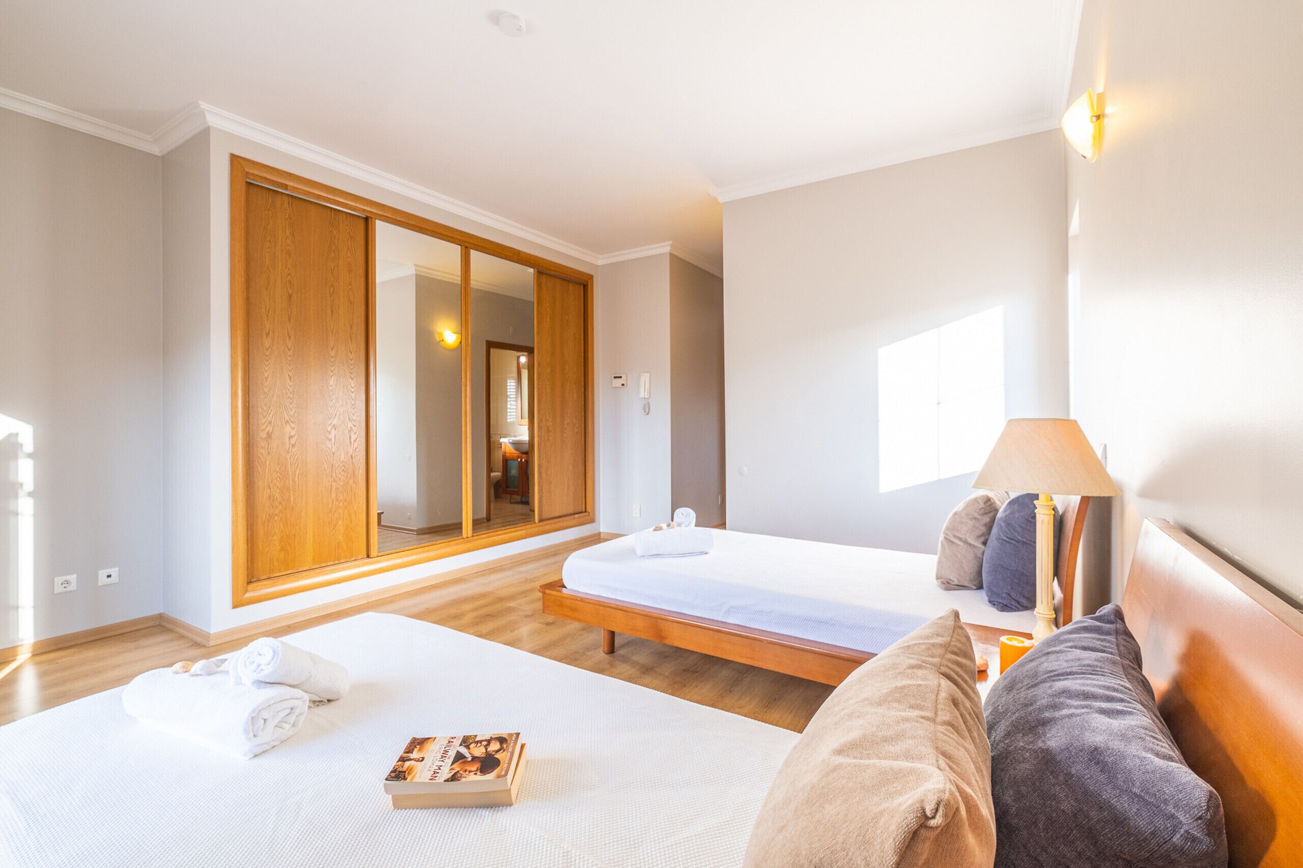 Une chambre d’hôtel avec une grande armoire, un lit avec un matelas blanc et une table de chevet avec une lampe.