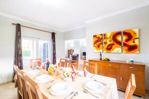 A dining area with a table set for six, wooden chairs, and a view of the living room through an open door.