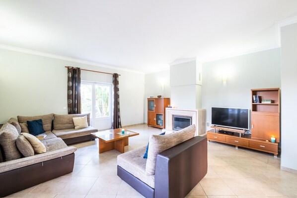A modern living room with a sectional sofa, a coffee table, a flat-screen TV, and a fireplace.