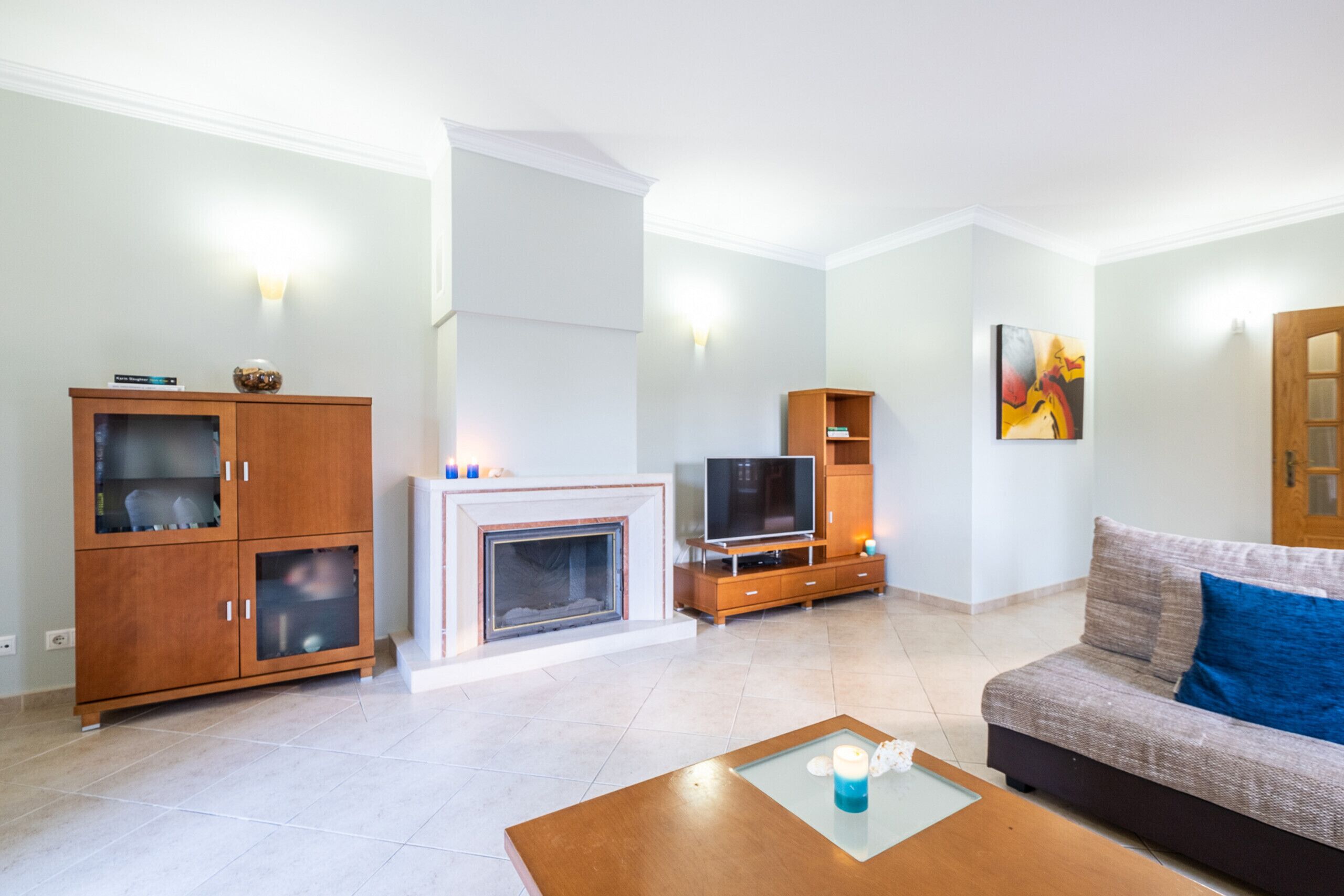 A living room with a fireplace, TV, sofa, and wooden cabinets.