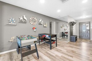 A room with a foosball table, a ping pong table, and a door with a window. - Winter Escape • Heated Pool & Spa • Near Beach (Palm Harbor)