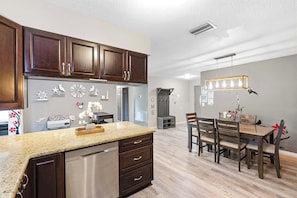 A modern kitchen with dark wooden cabinets, a stainless steel dishwasher, and a granite countertop.
