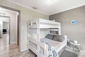 Ein Schlafraum mit Etagenbetten, einem kleinen Tisch und einem an der Wand hängenden Bild.