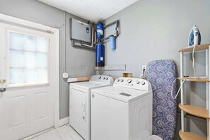 Une buanderie équipée de deux machines à laver, d’un sèche-linge et d’un chauffe-eau.