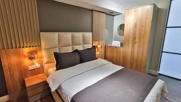 Un dormitorio moderno con una cama grande, cabecera de madera, lámparas de noche y un armario.
