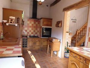 A compact kitchen with a tiled backsplash, wooden cabinets, a gas stove, and a built-in oven. - Gîte Les Bambous, Sologne getaway, nature & relaxation 10 min from Chambord (Crouy-sur-Cosson)