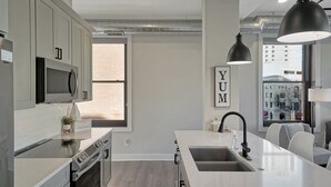 Een moderne keuken met een centraal eiland, roestvrijstalen apparatuur en een groot raam voor natuurlijk licht.