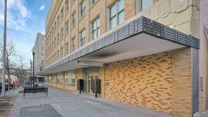 Een gebouw met een bakstenen gevel, een overdekte doorgang en een bank op de stoep.