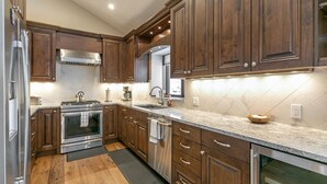 Une cuisine moderne avec des meubles en bois, des appareils électroménagers en acier inoxydable et un plan de travail en marbre.