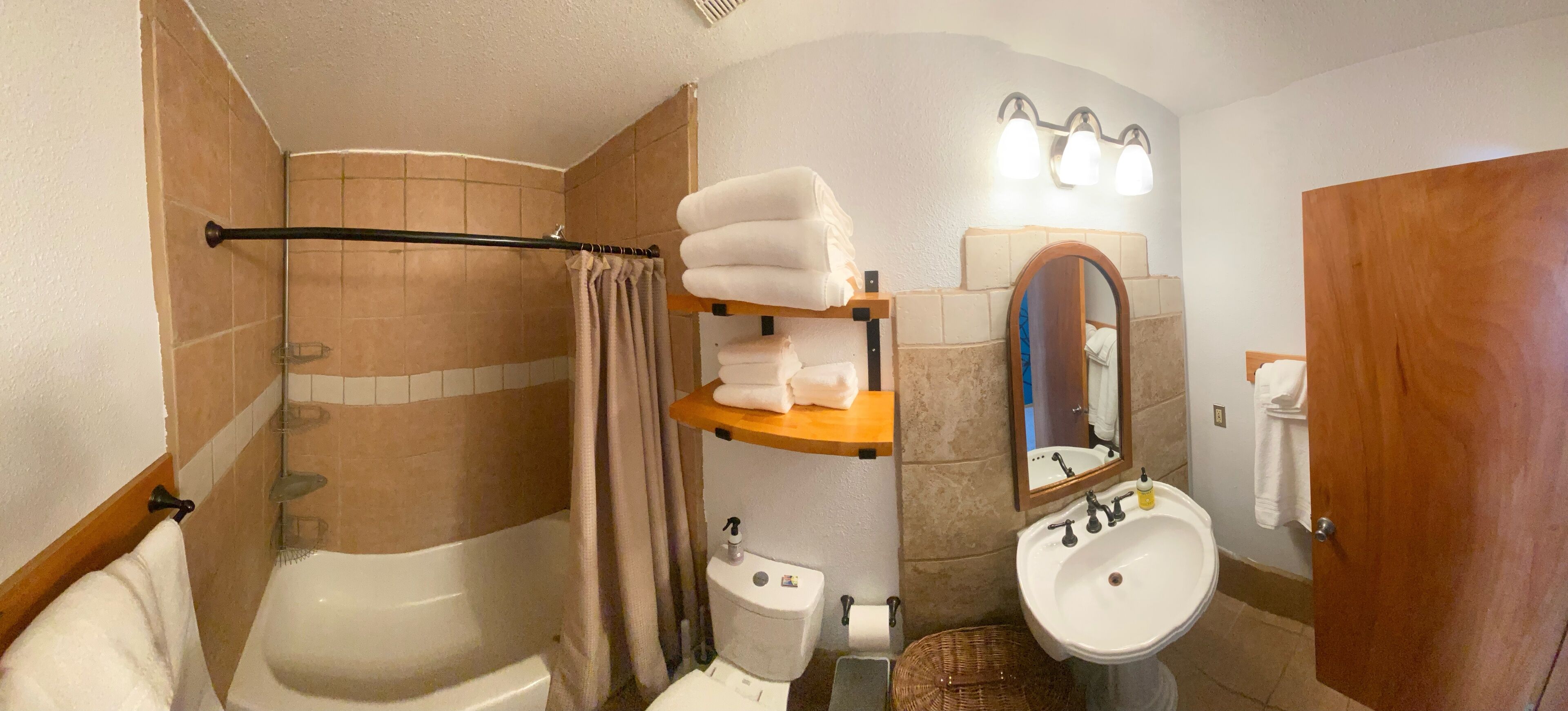 A bathroom with a bathtub, toilet, sink, and a shower area.