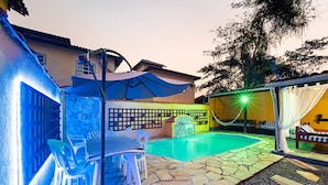 A swimming pool area with stone flooring, a table with chairs, and a hammock. - POUSADA ACQUA MARINA (Paraty)