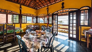 A dining area with a table set for four, surrounded by chairs, and large windows offering a view of the outdoors. - POUSADA ACQUA MARINA (Paraty)