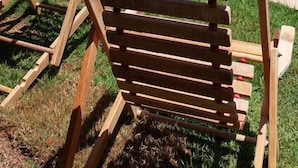 A wooden poolside chair with a clear view of a swimming pool and a grassy landscape in the background. - Casa Petronella (Pardinho)