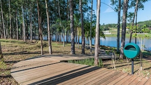 A wooden deck leading to a lake surrounded by tall trees. - Casa Petronella (Pardinho)