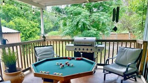 Ein Billardtisch mit Billardkugeln, ein Grill und Sitzgelegenheiten im Freien.