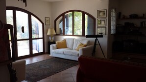 A living room with a white sofa, a floor lamp, a telescope, and large windows. - Cozy villa with sea view. (Peschici)