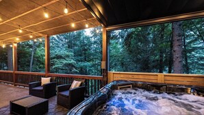 A hot tub area with wicker furniture and a view of a forest. - Ellijay River Access (Trout!) | Hot Tub| Firepit | Games | Dogs Welcome! (Cherry Log)