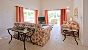 A spacious living room with two sofas, a coffee table, and a TV. - Bay House - 3 bedroom Villa, private pool and garden, near beaches (Saint Mary)