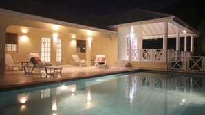 A swimming pool with lounge chairs and a covered seating area at night. - Bay House - 3 bedroom Villa, private pool and garden, near beaches (Saint Mary)