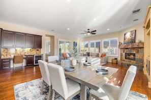 A spacious kitchen with dark wooden cabinets, a granite countertop, and a dining area with a wooden table and chairs. - Endless Summer - Swim up bar & waterslide! (Indio)