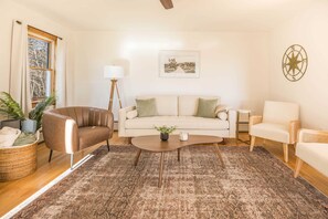 A living room with a sofa, armchairs, a coffee table, a floor lamp, and a large window. - 4-Season Waterfront Oasis Acadia with Hot Tub (Franklin)