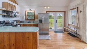 Una cucina moderna con mobili in legno, elettrodomestici in acciaio inossidabile e un'isola grande. C'è una porta scorrevole in vetro che dà su un balcone con vista sull'esterno.