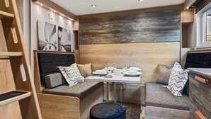 A compact, modern RV interior with a dining area, seating, and artwork. - The Escape - Luxury Pod, Close to Beach (Wisemans Bridge)