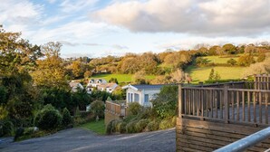 A residential area with houses, a wooden deck, and a gravel driveway. - The Escape - Luxury Pod, Close to Beach (Wisemans Bridge)