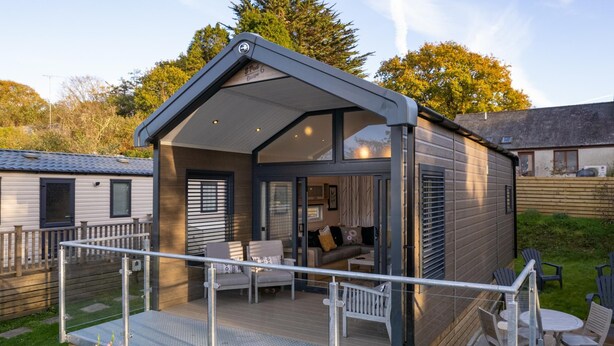 A modern, compact mobile home with a covered deck and outdoor seating area. - The Escape - Luxury Pod, Close to Beach (Wisemans Bridge)