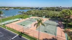 Una cancha de tenis con vista despejada a un puente y un paisaje urbano al fondo.