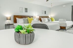 A modern hotel room with a bed, bedside tables, and a potted plant on a round table. - The Lodge at Lookout Mountain (Chattanooga)