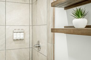 A bathroom with a tiled wall, a shower control panel, and a shelf with a potted plant. - The Lodge at Lookout Mountain (Chattanooga)