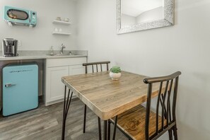 A compact kitchen with a wooden table, two chairs, a blue refrigerator, a sink, and a mirror on the wall. - The Lodge at Lookout Mountain (Chattanooga)