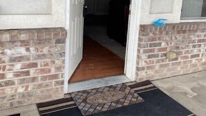 Una entrada residencial con fachada de ladrillo, puerta blanca y felpudo.