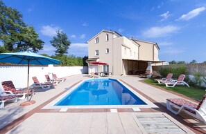 A swimming pool with lounge chairs, a covered patio area, and a two-story building in the background. - ⭐ Beautiful holiday villa for groups ⭐ (Cere)