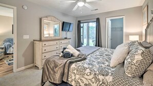 A bedroom with a bed, a dresser, a ceiling fan, a television, and a window with curtains. - True Blue Golf Resort Condo - 3 Mi to Beach! (Pawleys Island)