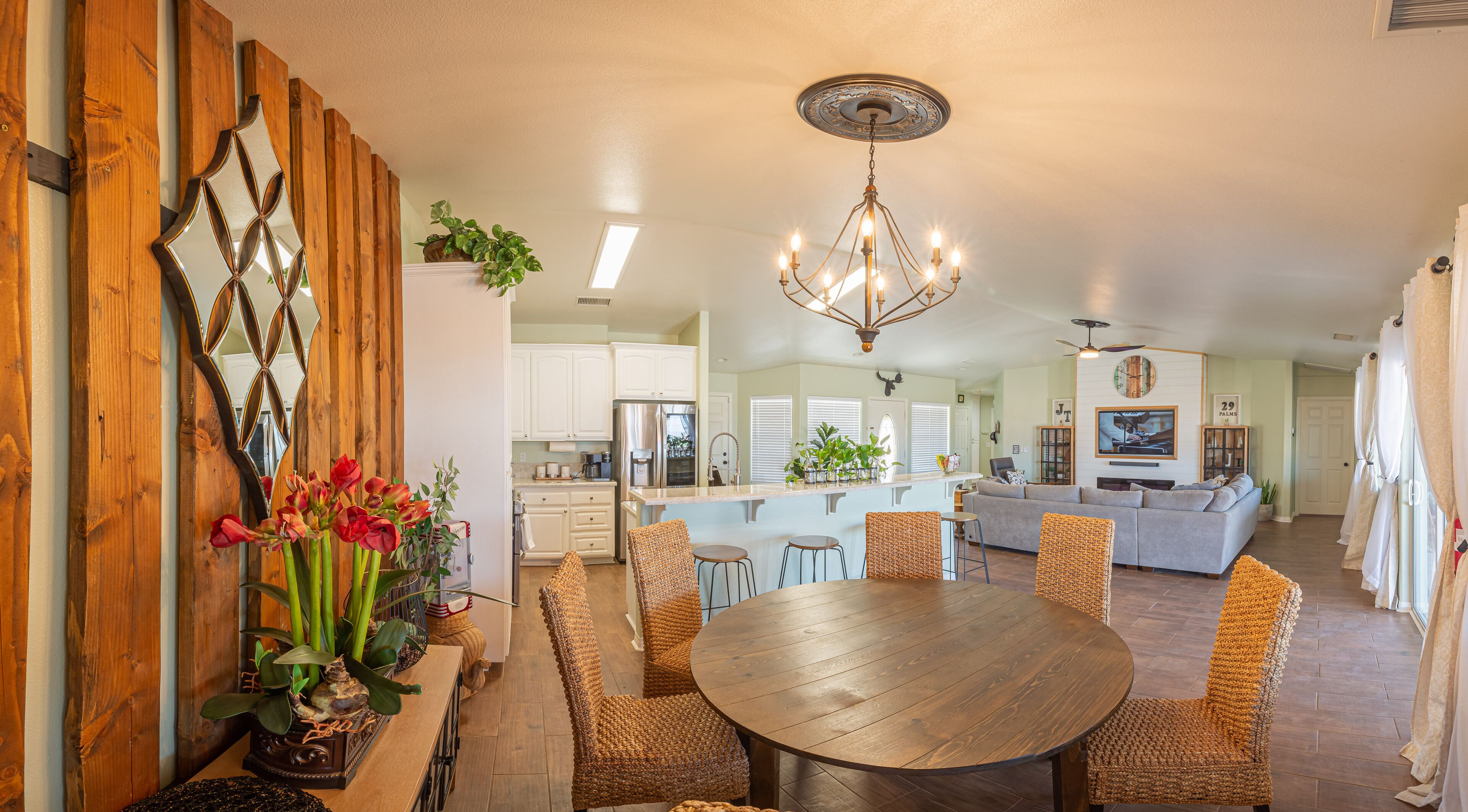 A spacious living area with a dining table, wicker chairs, and a chandelier.