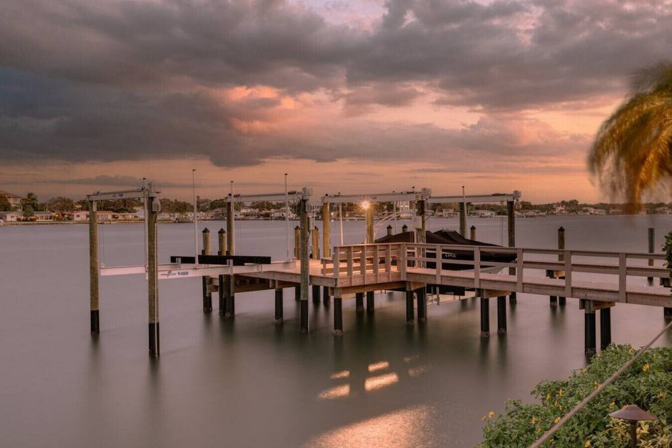 A pier extending into calm water with a cloudy sky above.