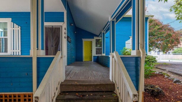A blue building with a porch, wooden steps, and a yellow door. - The Sunset|Pet-Friendly Downtown 1BR · Easy Entry · Patio Access · (Eugene)