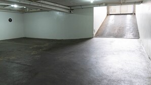 Un garaje para estacionar con pisos de concreto, techo inclinado y una ventana en la pared derecha.