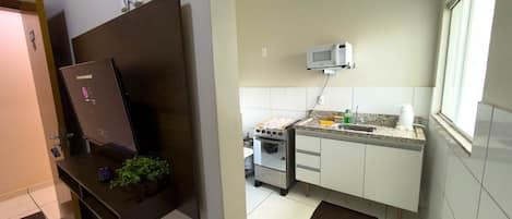 Een keuken met een magnetron, spoelbak en fornuis.
