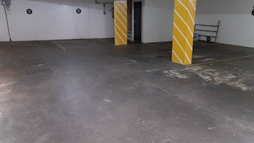 Ein unterirdischer Parkbereich mit Betonboden und gelb gestreiften Säulen.