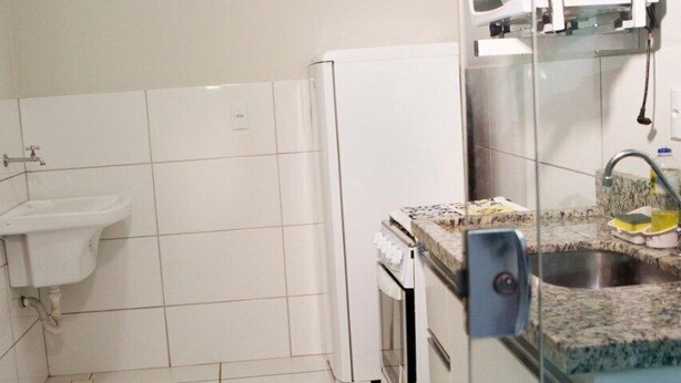 Una cocina con armarios blancos, microondas, fregadero y estufa.