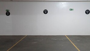 Un garaje de estacionamiento con espacios delimitados y señalización direccional.