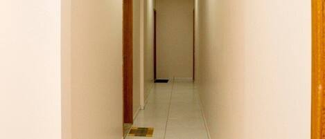 A narrow, well-lit hallway with a tiled floor and wooden doors on both sides.
