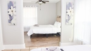A hotel room with two beds, a ceiling fan, and artwork on the walls. - Modern Style Minimalistic Home! (Dallas)